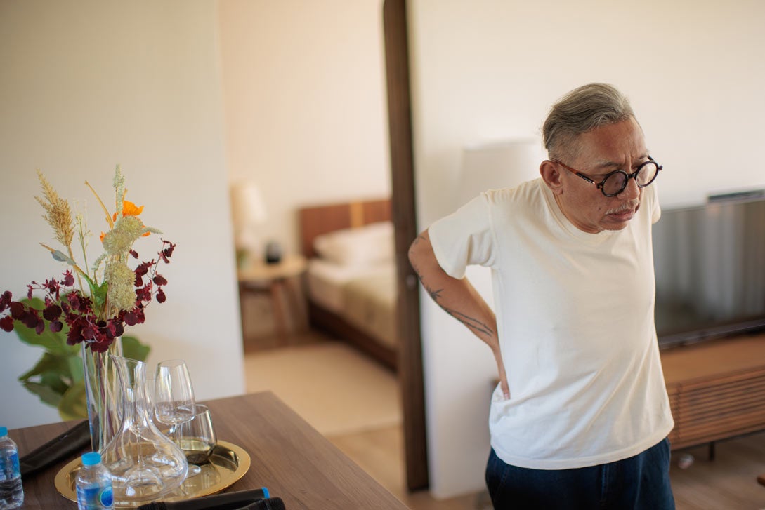 Older man in glasses with back pain at home