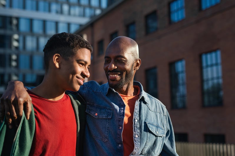 Father and son walking with father's arm arm around him and smiling