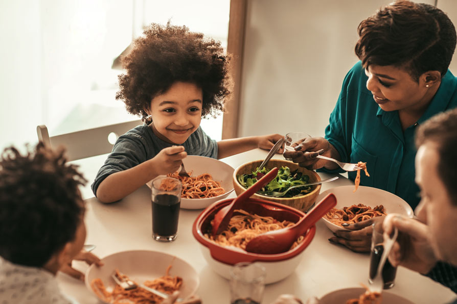 Family sitting around a table eating spaghetti together