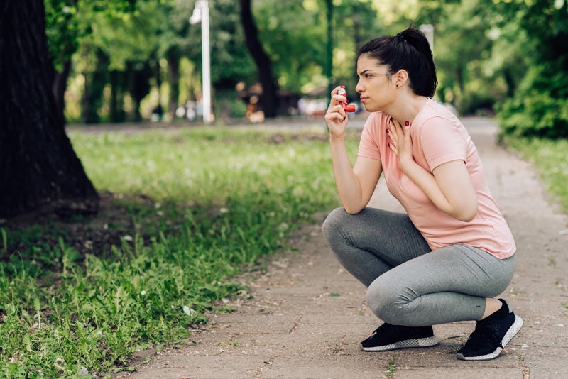 Girl using asthma inhaler during jogging