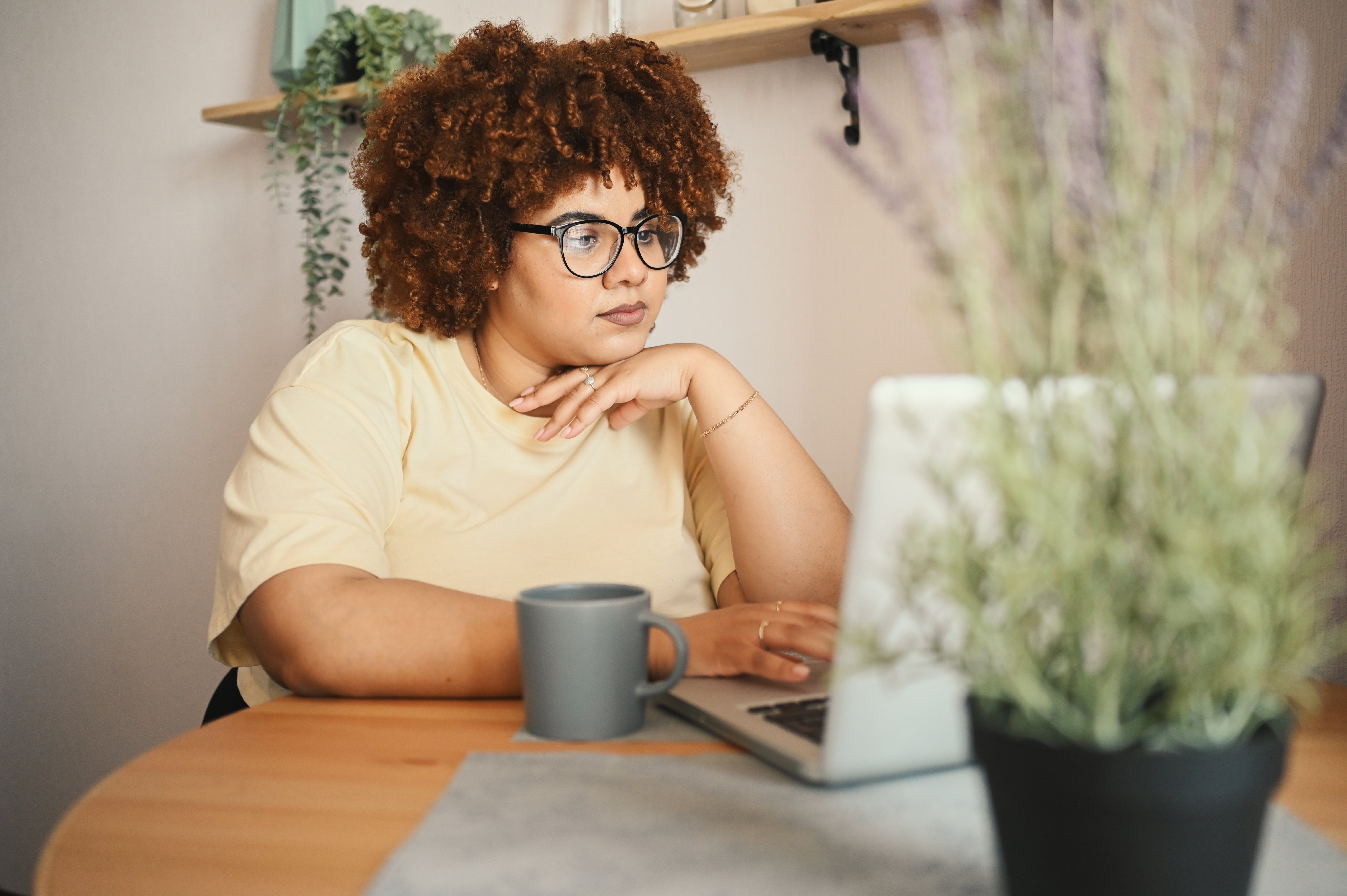 A young woman works on her laptop with a serious expression