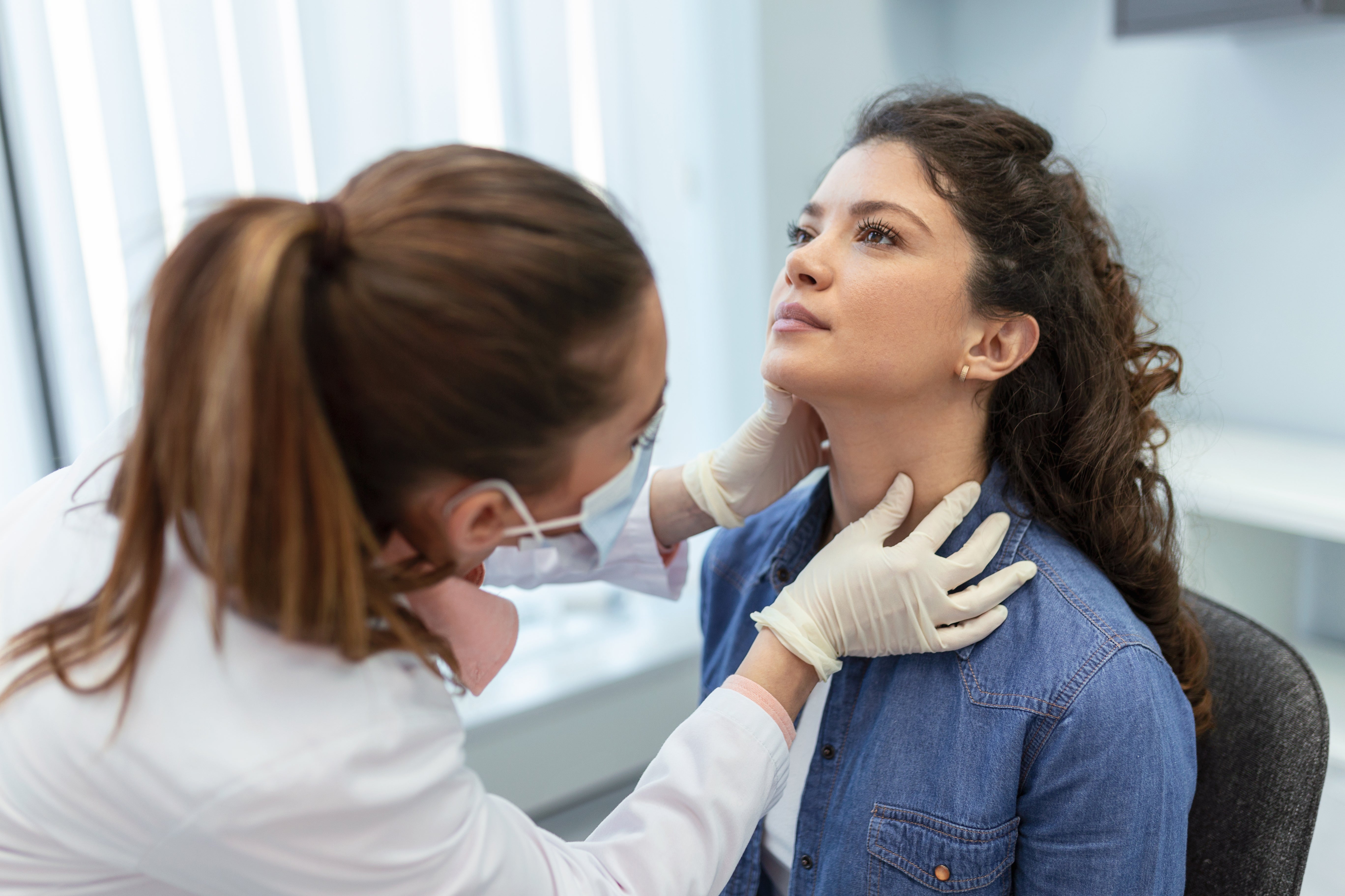 A doctor examines a young woman's neck 
