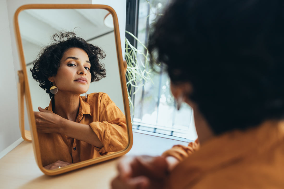 Latin-American female looking at skin in mirror