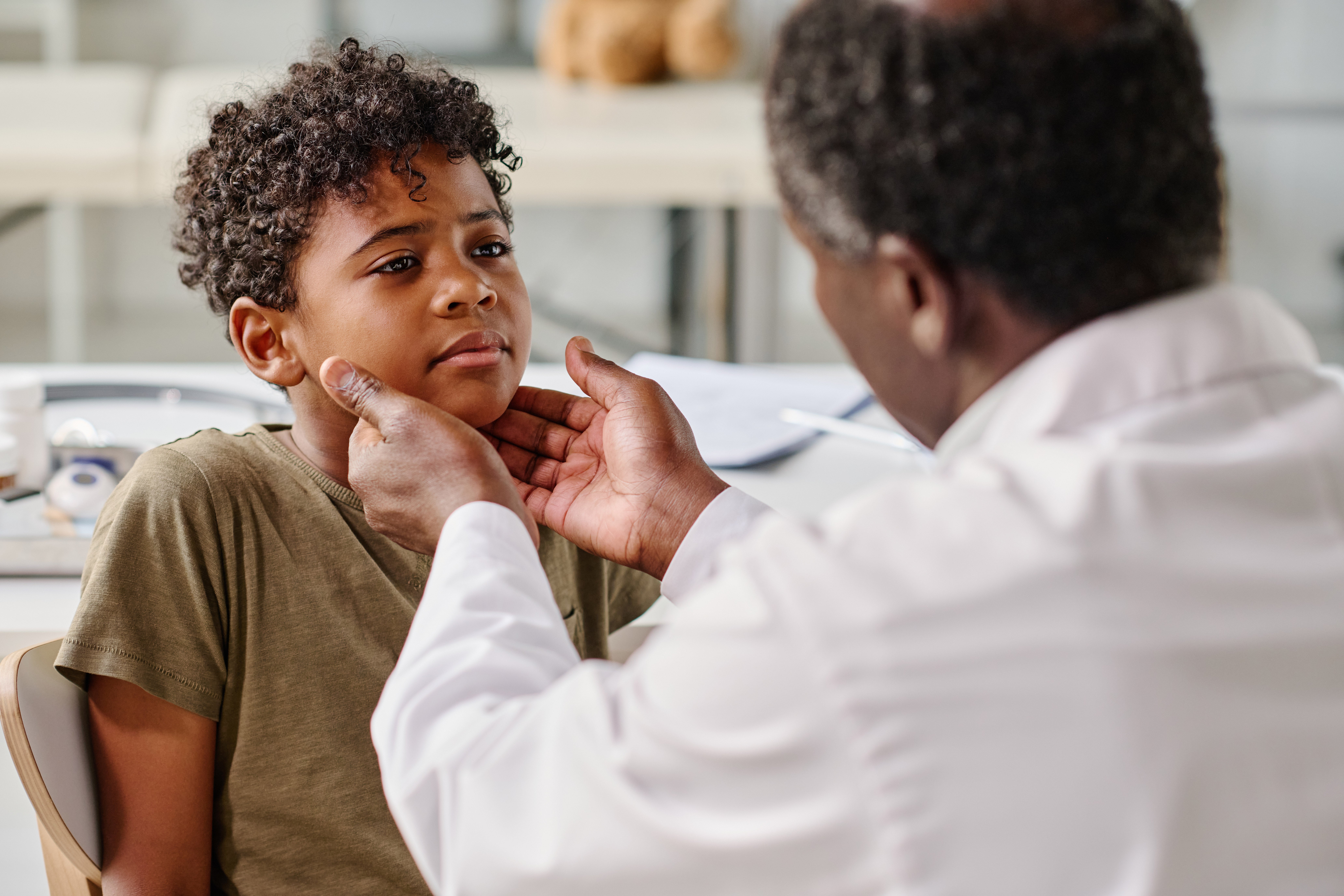 A doctor feels a child's neck to examine him for tonsillitis 