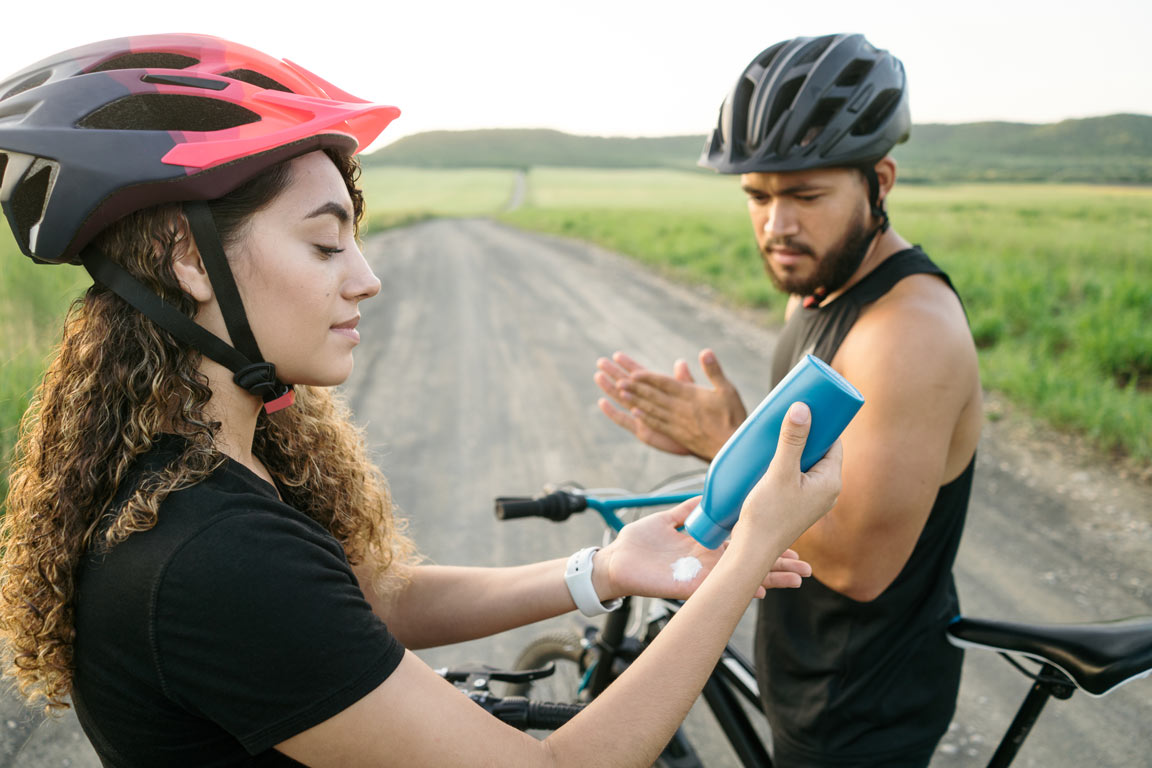 Latin young couple putting on sunscreen before cycling