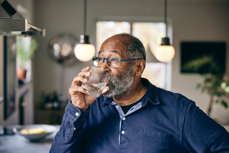 African-American man drinking water in kitchen