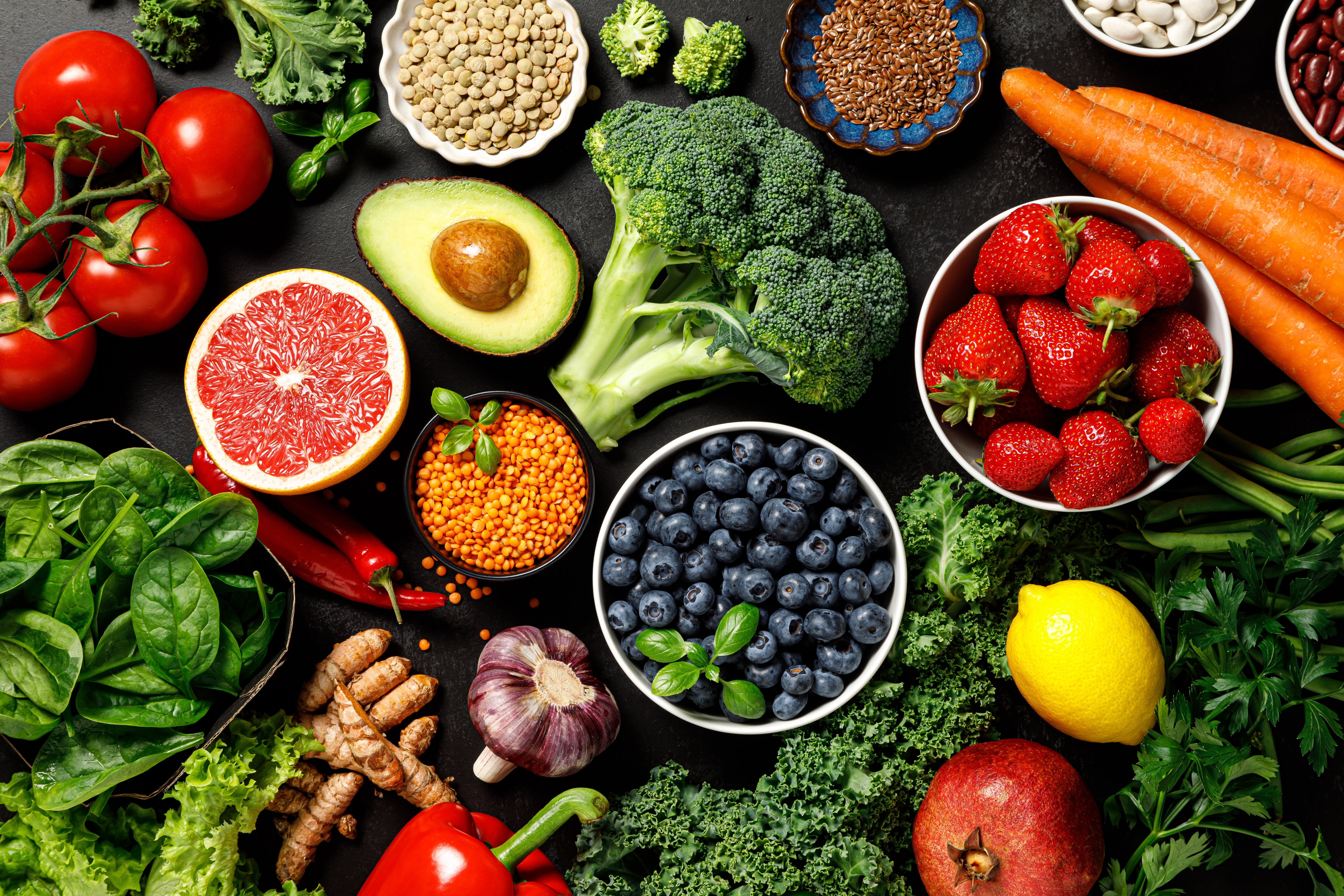 A variety of fruits and vegetables, including broccoli, blueberries, an avocado, a grapefruit, and more