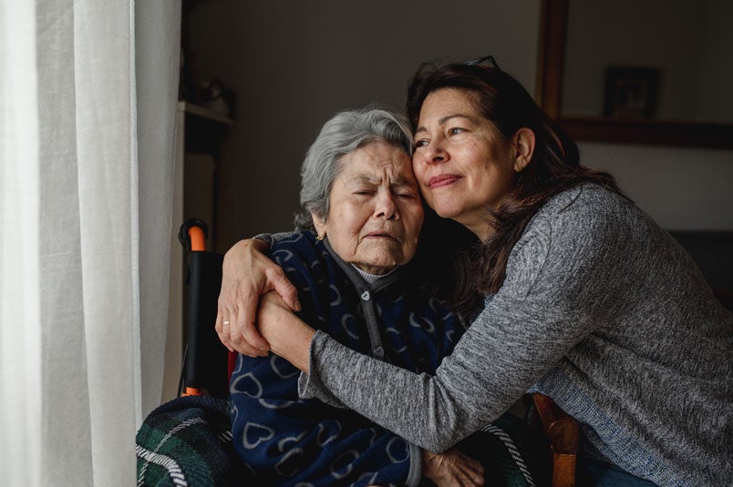 A middle-aged woman embraces her mother at home