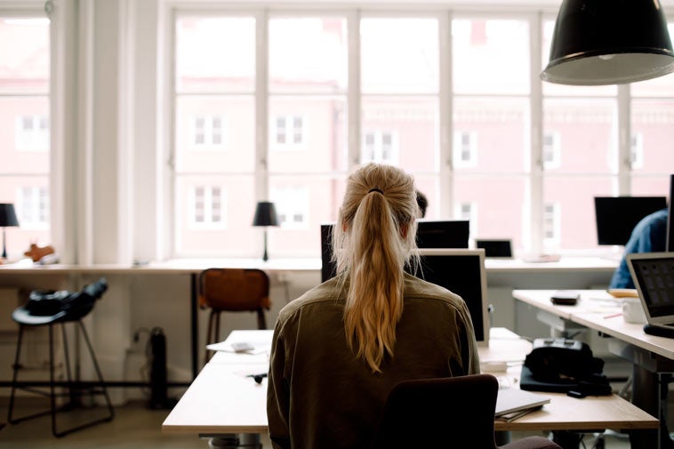 Rearview of blonde woman at desk in an office