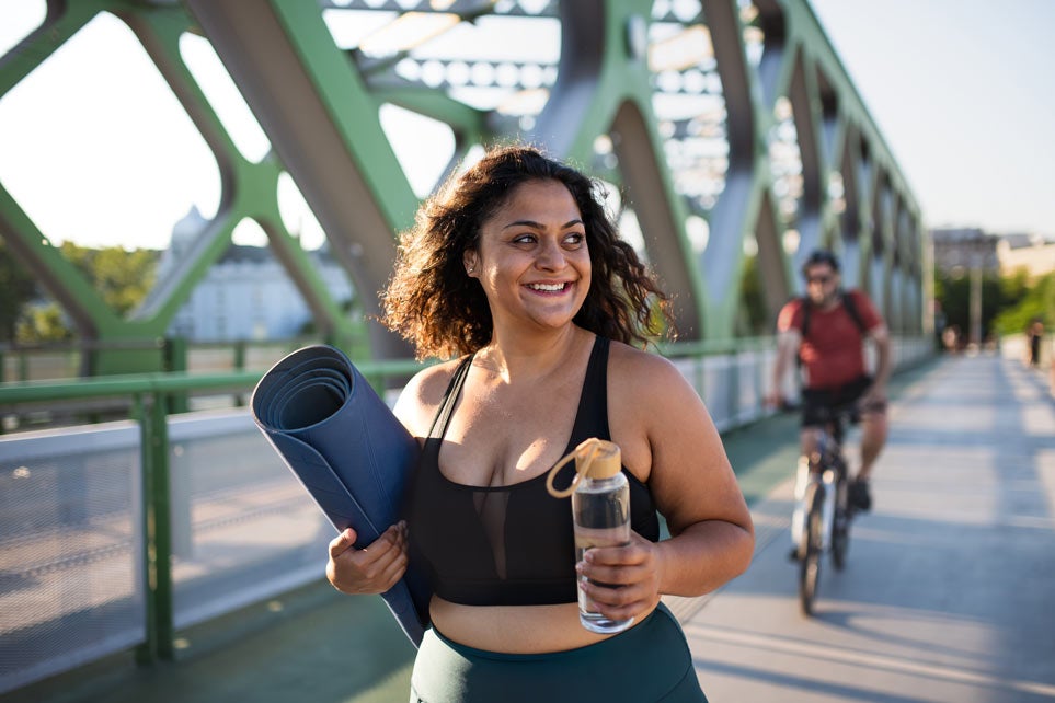 Portrait of beautiful young overweight woman walking outdoors on a city bridge.