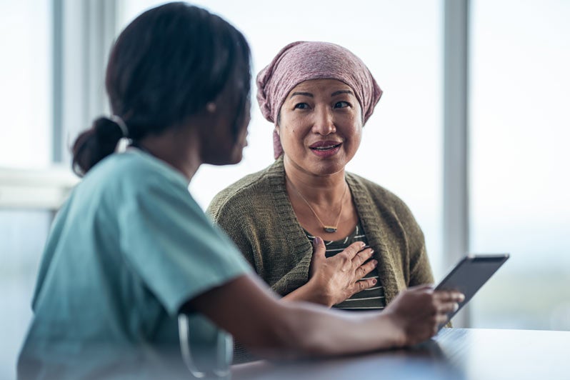 Woman in head scarf speaking with physician in scrubs