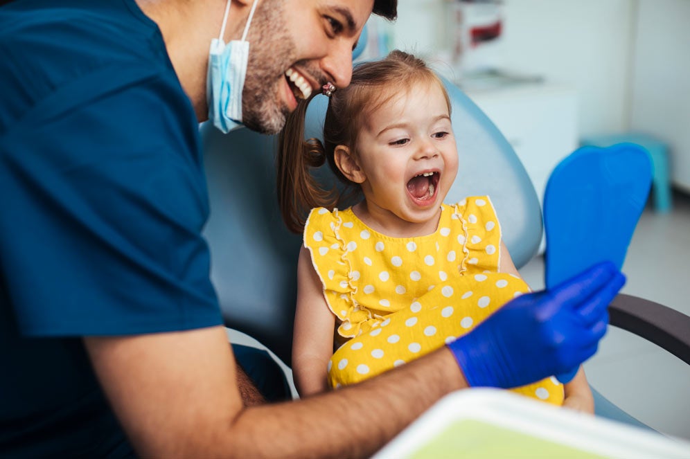 Dentist showing toddler her teeth in mirror
