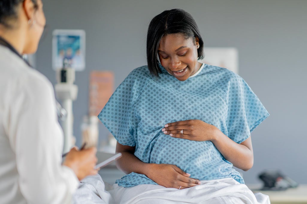 Pregnant woman in a hospital gown at in-office check-up