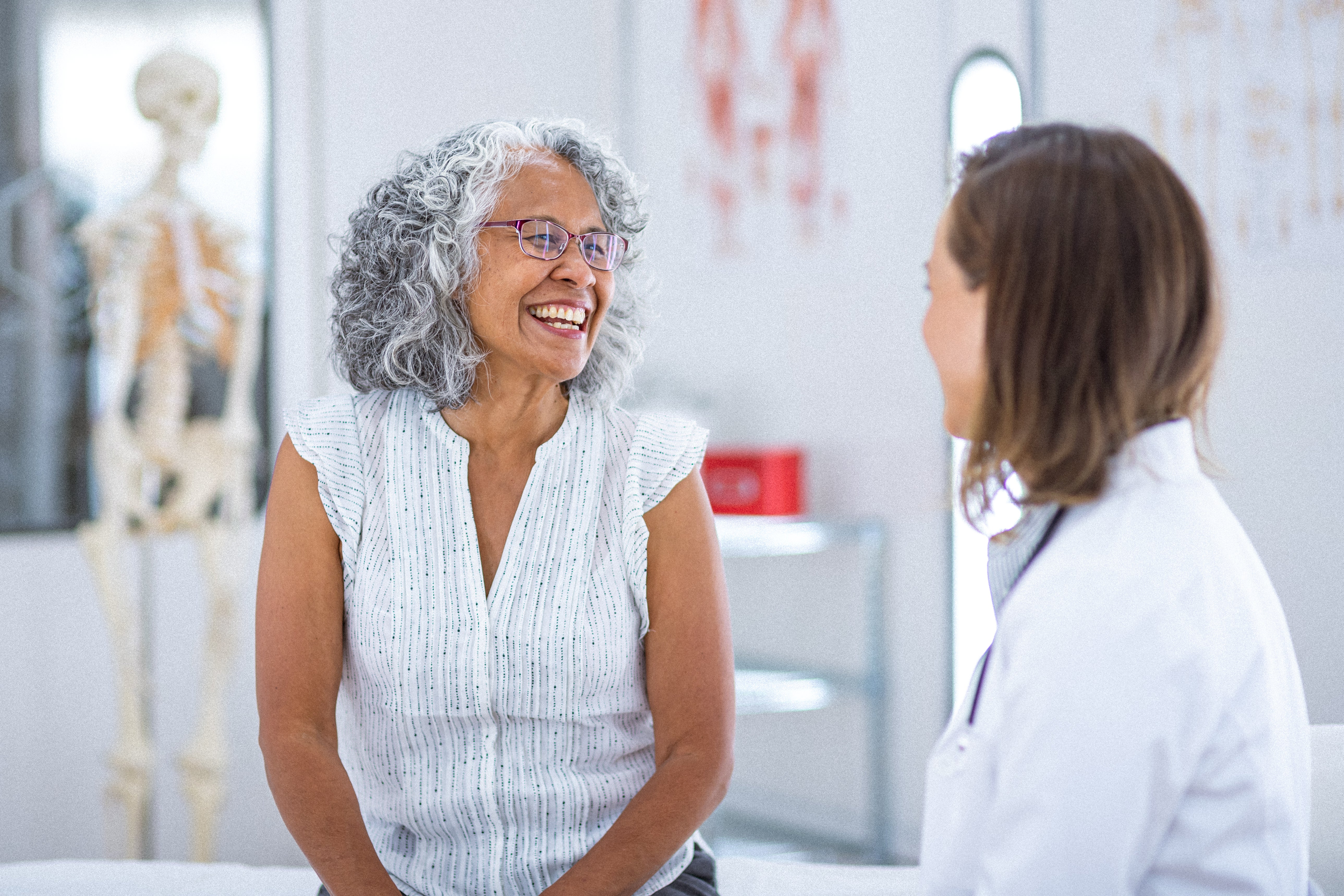 An older woman smiles as she talks with her doctor