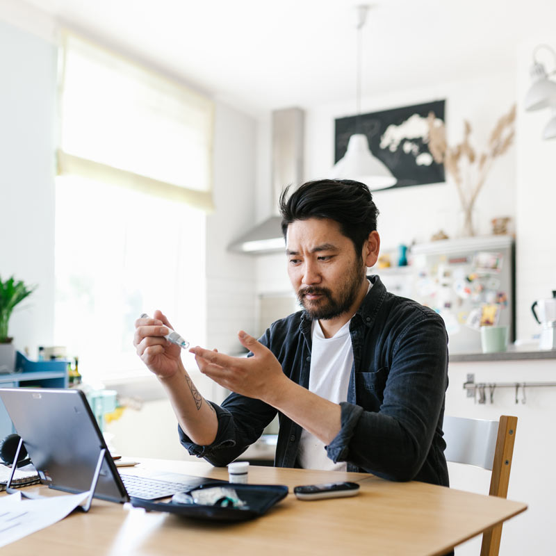 Man checking blood sugar in his kitchen